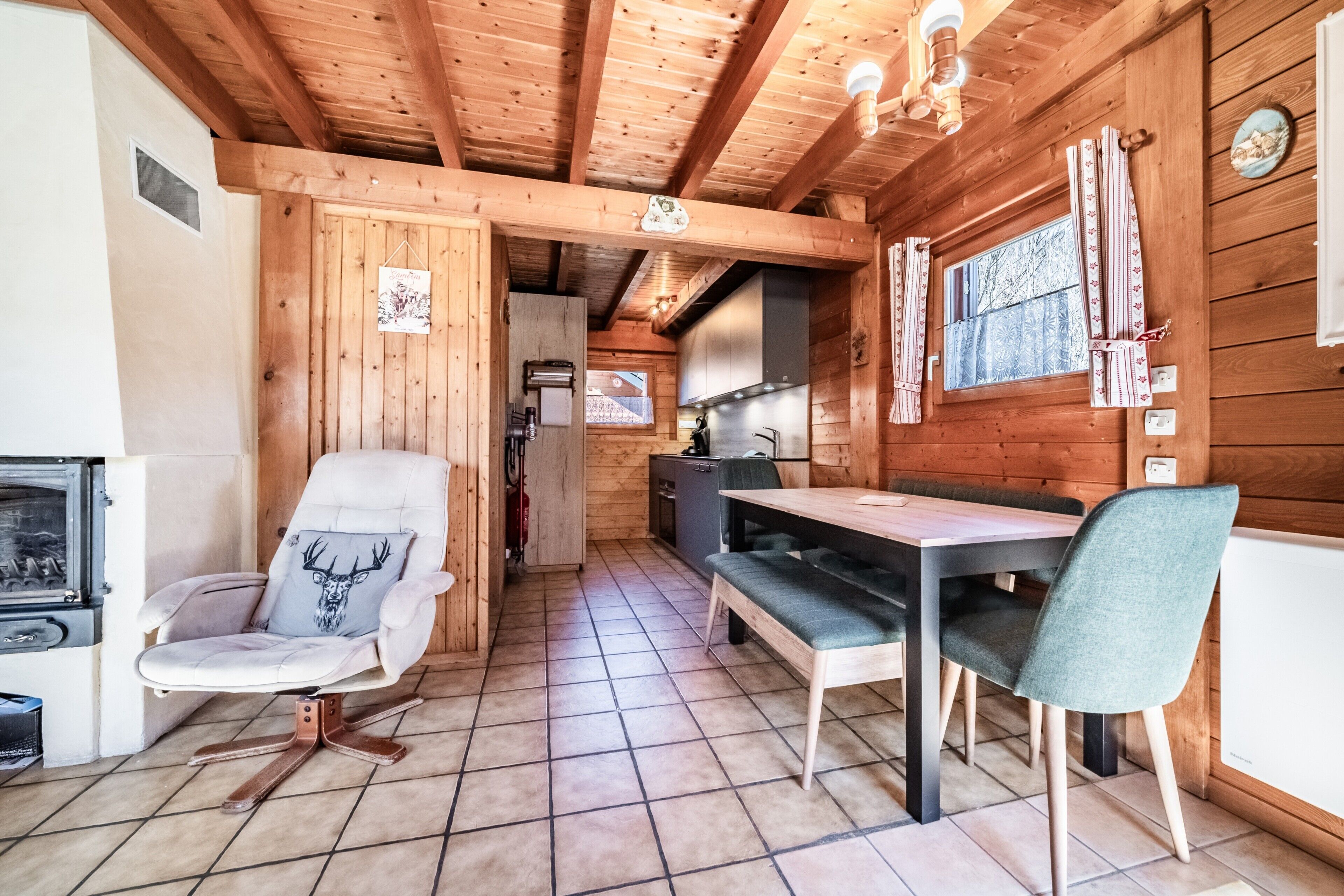 Interno di una baita in legno con zona pranzo, cucina e camino.