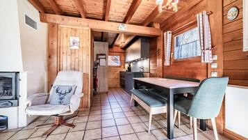 Interno di una baita in legno con zona pranzo, cucina e camino.
