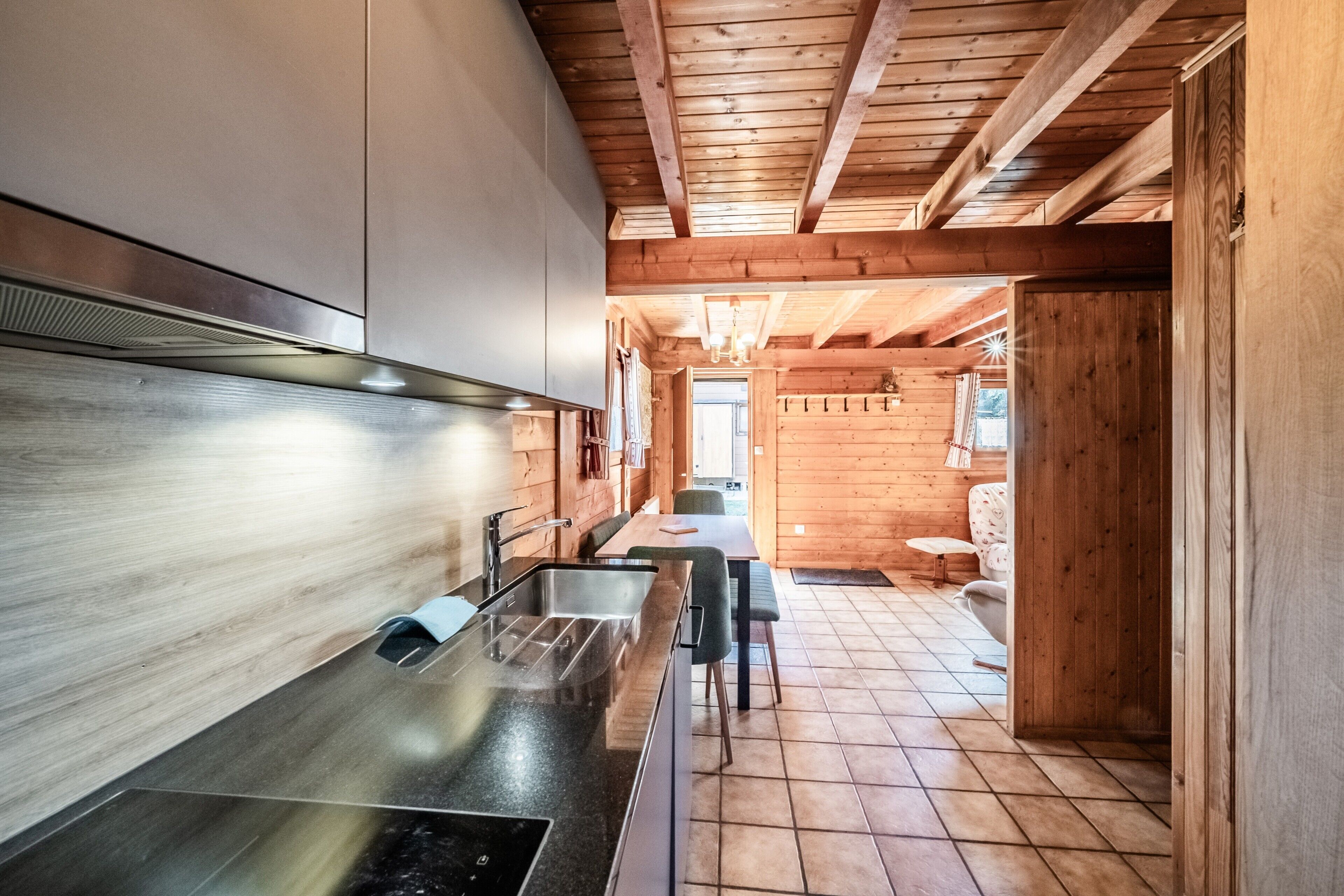 Una cucina moderna con lavello in acciaio inossidabile, mobili in legno e soffitto in legno.