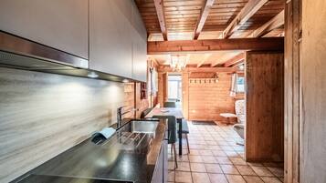 Una cucina moderna con lavello in acciaio inossidabile, mobili in legno e soffitto in legno.