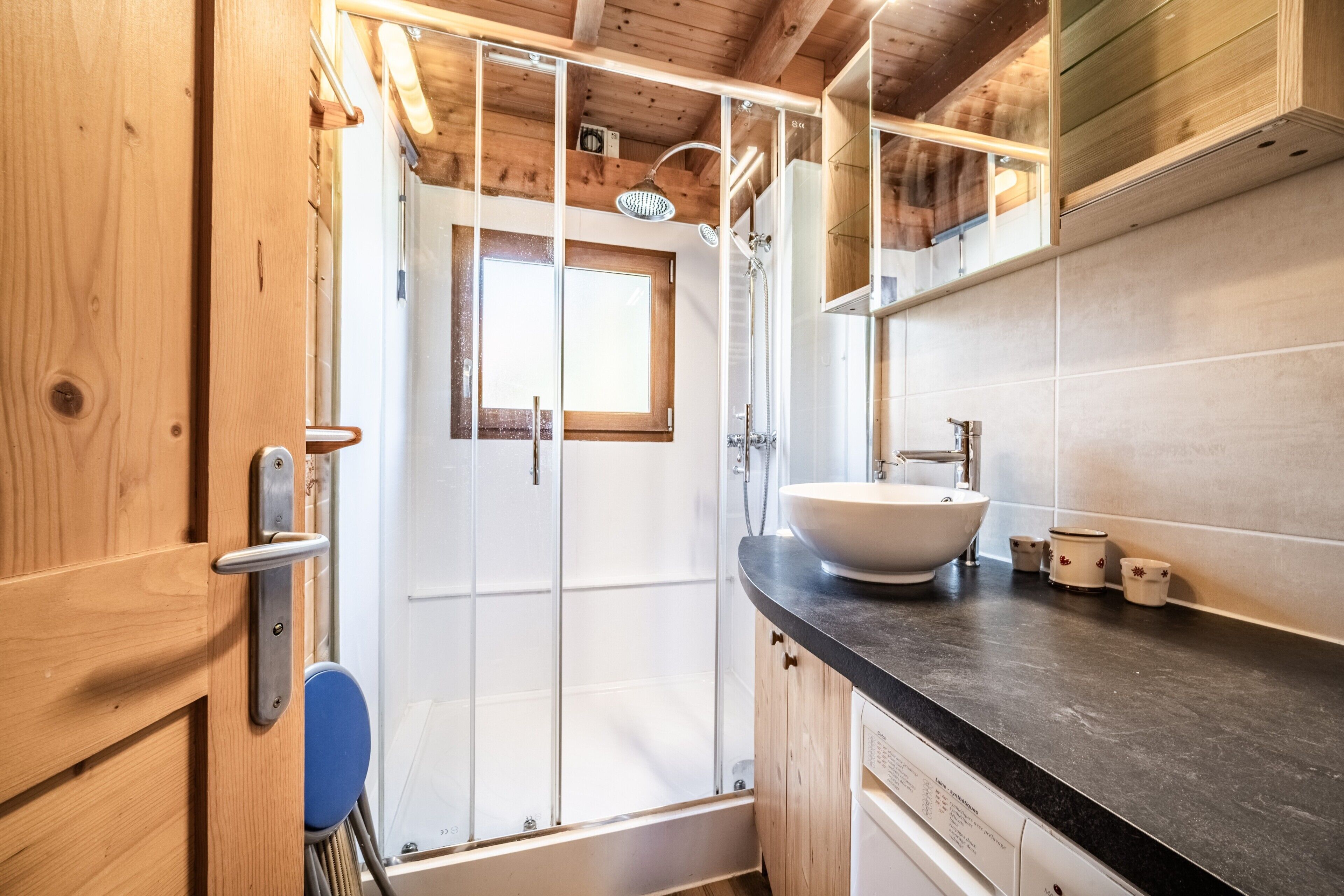 Un interior de madera con ducha, lavabo y ventana.