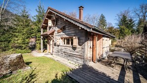 Eine rustikale Holzhütte mit Schornstein, einer Terrasse und einem Tisch mit Stühlen.