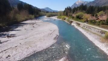 Un fiume con acque cristalline, una spiaggia sabbiosa e un ponte con edifici a destra.