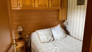 Una stanza con rivestimenti in legno, un letto, un comodino e una lampada.