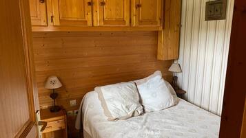 Una stanza con rivestimenti in legno, un letto, un comodino e una lampada.