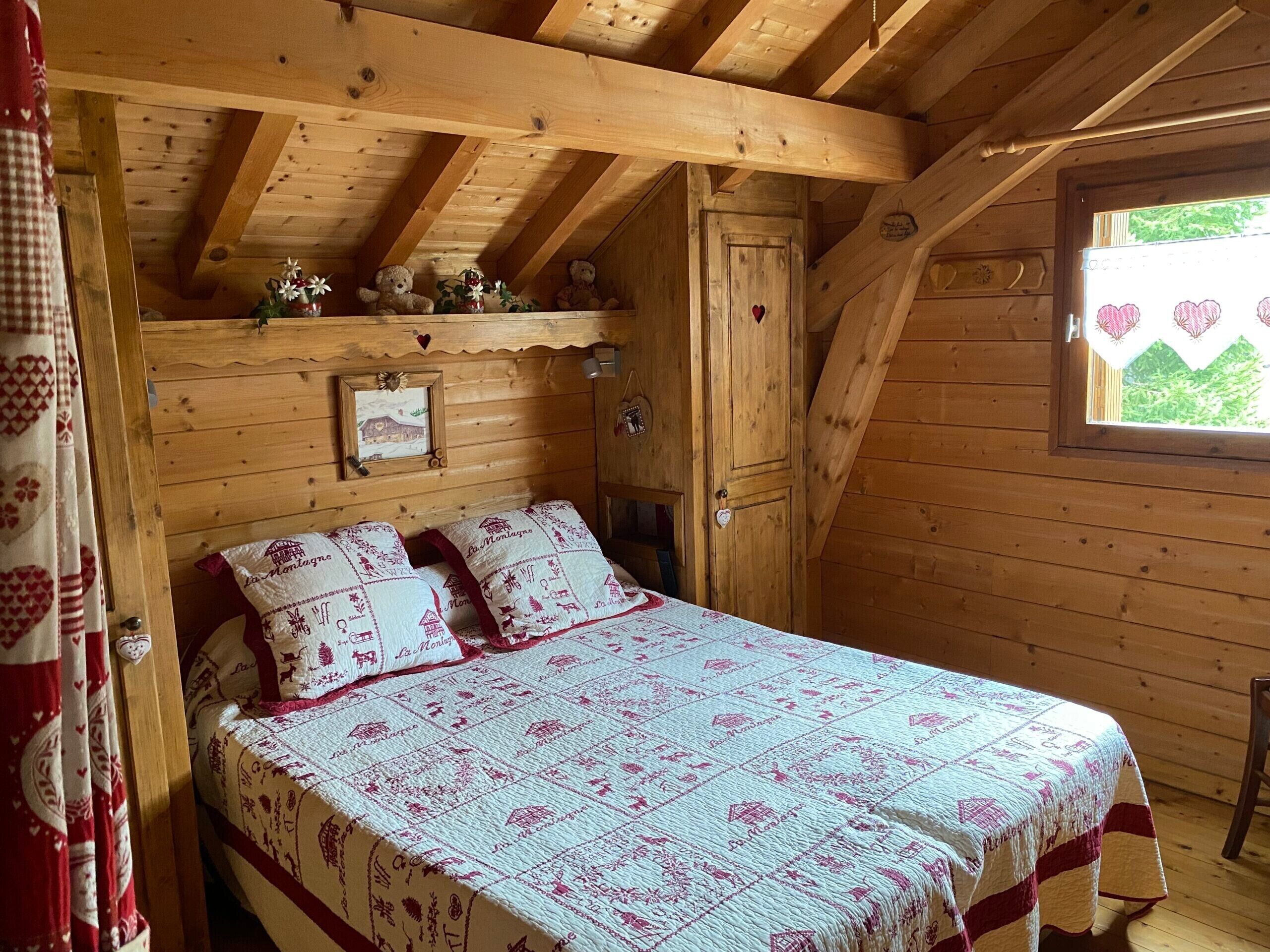 A wooden cabin bedroom with a bed, a window, and a door.