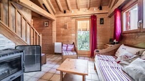L’intérieur d’un chalet en bois, avec un lit, une table, une chaise et une cheminée.
