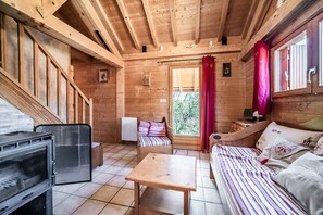 Ein Holzhütten-Interieur mit einem Bett, einem Tisch, einem Stuhl und einem Kamin.