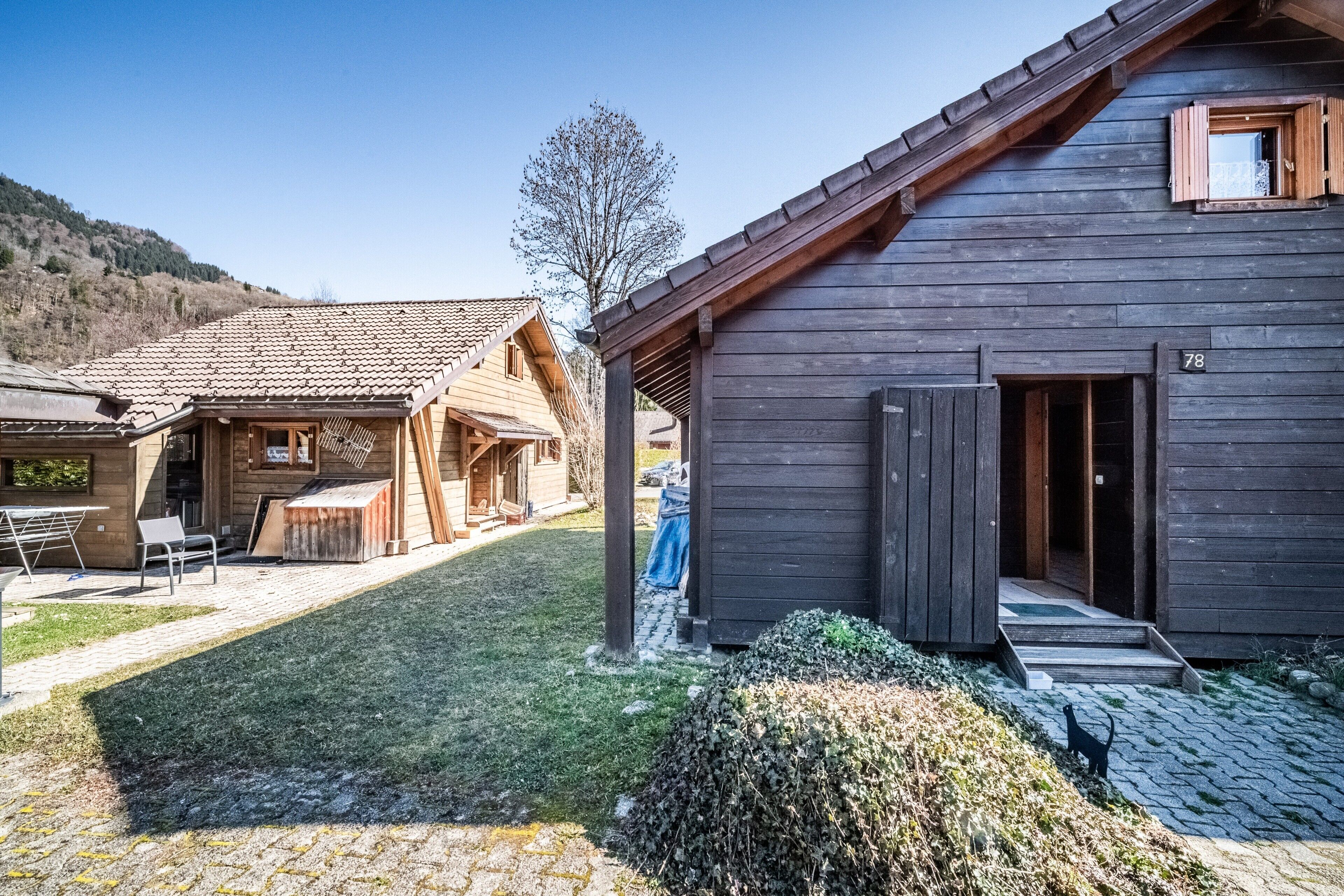 Un edificio rustico in legno con tetto in tegole, un cartello con il numero '78' e un piccolo portico.