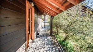 Une façade en bois, un porche couvert et un chemin pavé menant à une porte.
