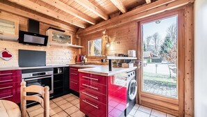 L’intérieur d’un chalet en bois comprend une cuisine, un coin repas et une grande porte-fenêtre coulissante donnant sur l’extérieur.