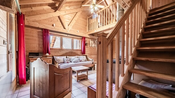 Un intérieur en bois comprenant un lit, un canapé et un escalier.