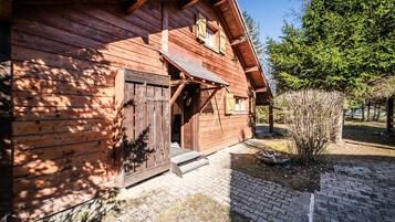 Une cabane en bois avec une porte en bois, un petit porche et un chemin de briques menant à l’entrée.