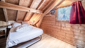 Ein Zimmer einer Holzhütte mit einem Bett, einem Fenster und einem roten Vorhang.