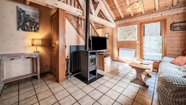 Ein Holzhütten-Innenraum mit Kamin, Fernseher und einer gemütlichen Sitzecke.