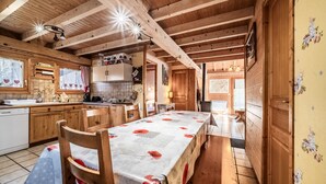 Ein Holzblock-Innenraum mit Esstisch, Küchenzeile und Holzbalken an der Decke.