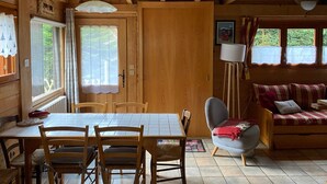 L’intérieur d’un chalet en bois, avec une table à manger, des chaises, un canapé et une lampe.