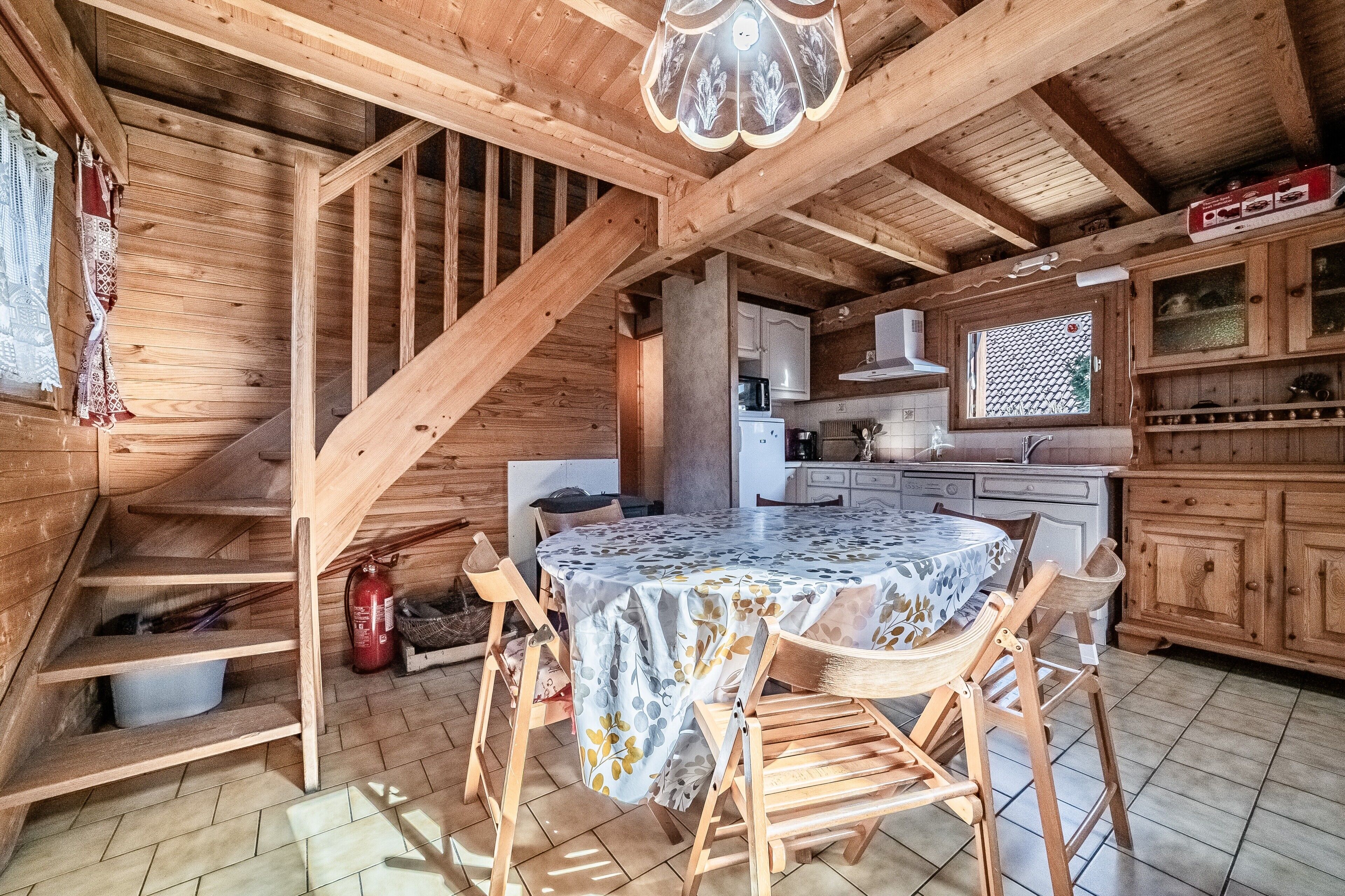 Un interior de madera con una mesa de comedor, sillas, una escalera y una zona de cocina.