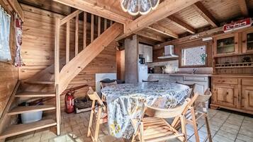 A wooden interior with a dining table, chairs, a staircase, and a kitchen area.