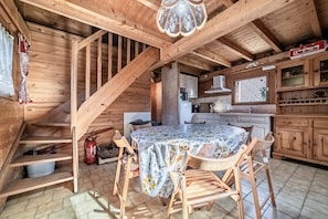 A wooden interior with a dining table, chairs, a staircase, and a kitchen area. - Chalet “6p Classique - Les Biches”: Mountain View, Private Terrace & Wi-Fi (Verchaix)