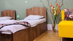 A room with two beds, a yellow sofa, a vase with flowers, and a framed picture on the wall. - City Guli Hostel (Tbilisi)