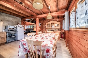 L’intérieur d’un chalet en bois comprend une table à manger, des chaises, un coin cuisine et une cheminée.