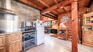 A wooden cabin interior with a kitchen, dining area, and a fireplace.