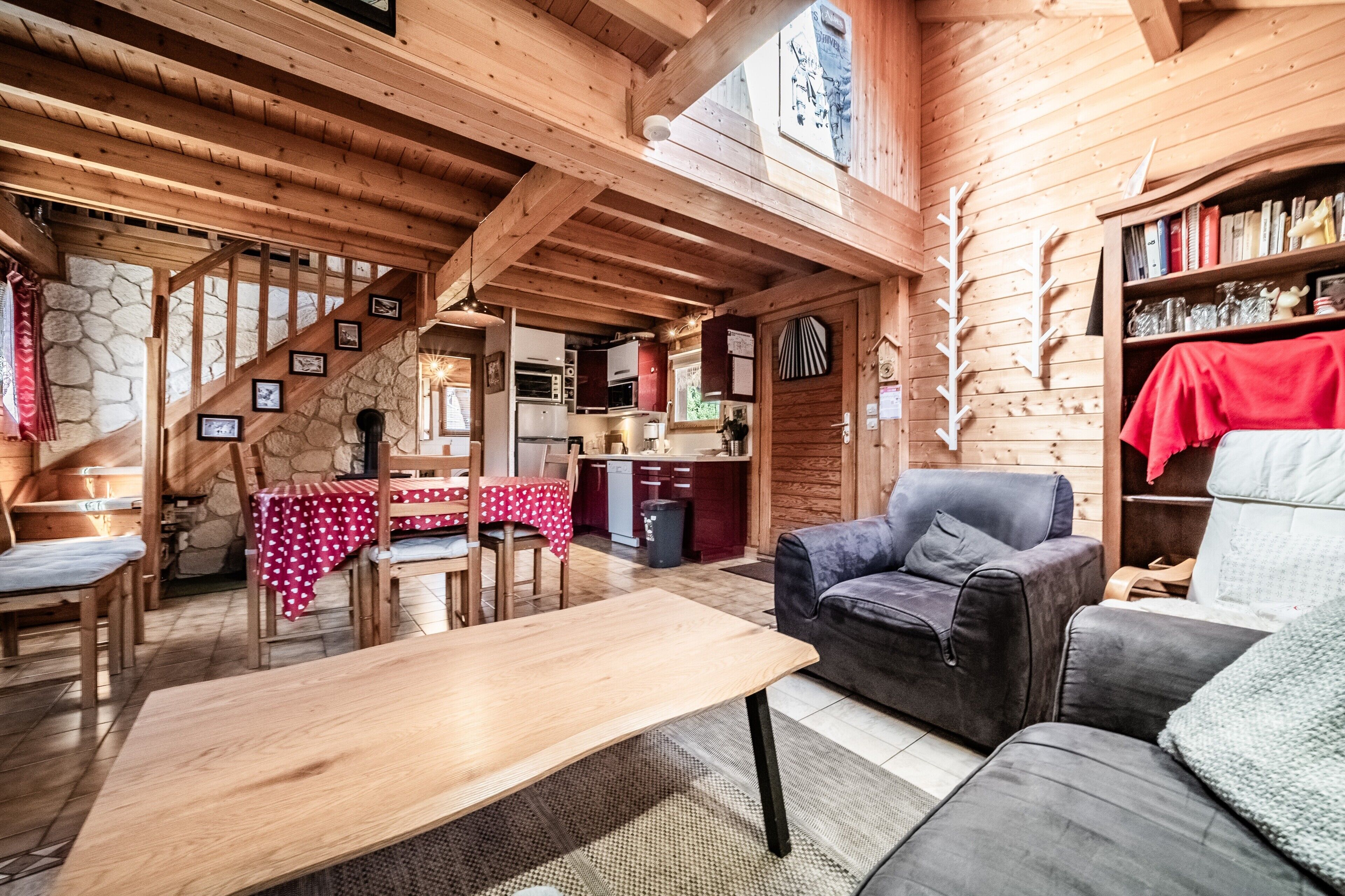 Un interior de madera con comedor, un sofá y una cocina visible a través de un umbral abierto.