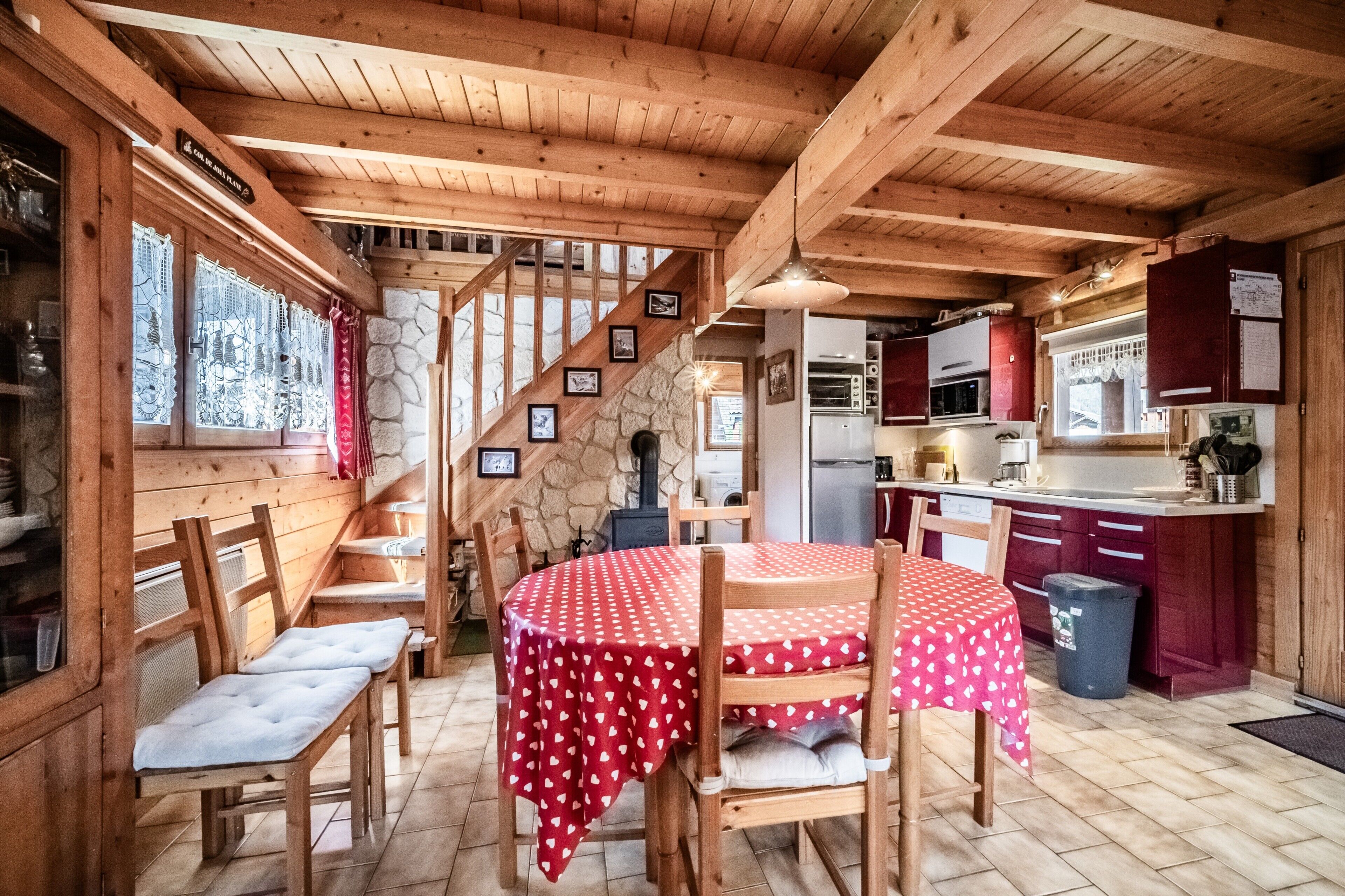 Un interior de madera con una mesa de comedor, sillas, una escalera y una zona de cocina.