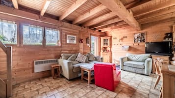 A wooden cabin interior with a sofa, a television, and a fireplace.