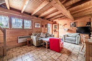 Ein Holzblockhaus-Innenraum mit einer Couch, einem Fernseher und einem Kamin.
