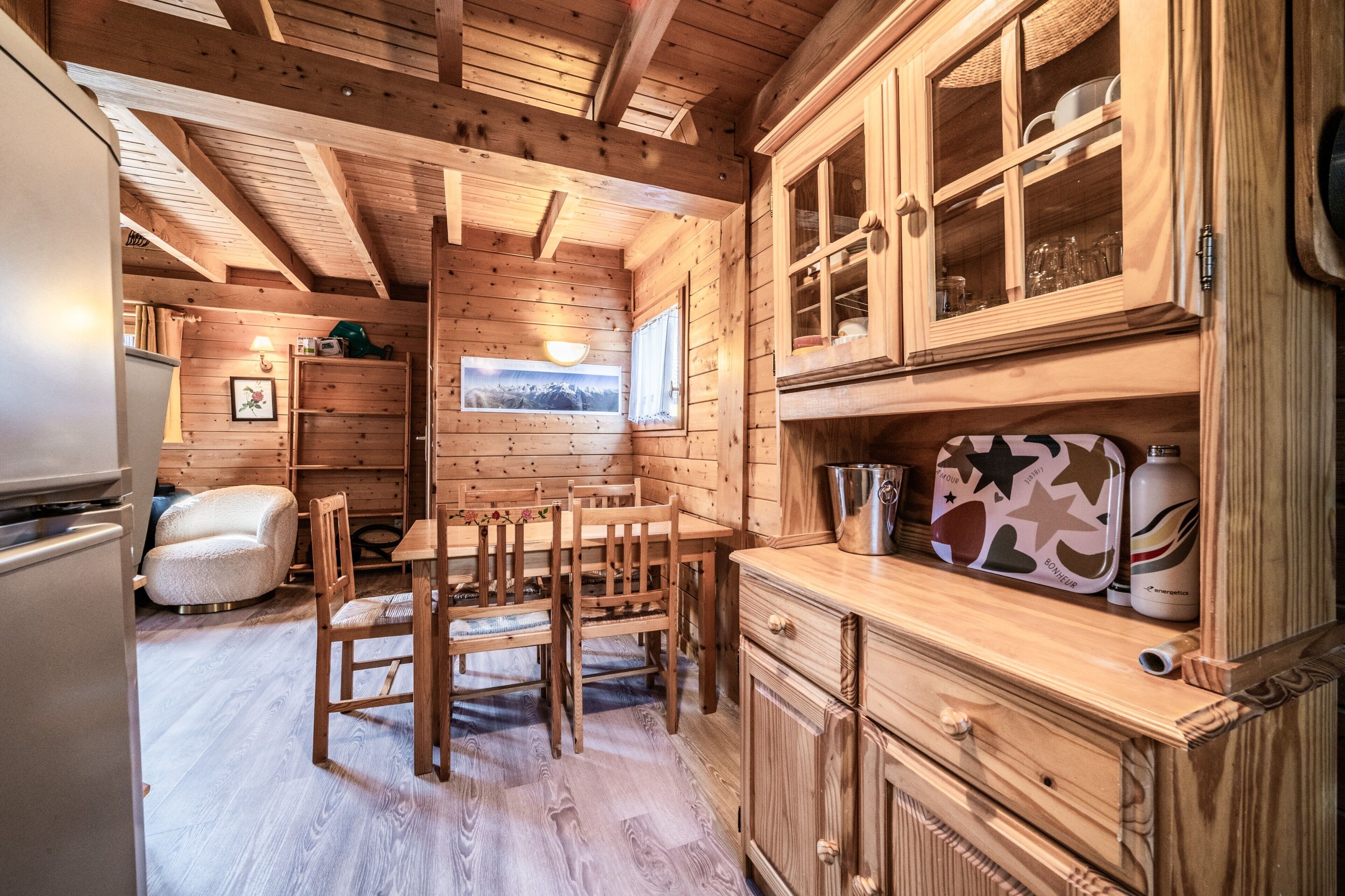 Ein Holzblock-Innenraum mit Essbereich, Küche und einem Fenster mit Bergblick.