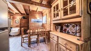 L’intérieur d’un chalet en bois comprend un coin repas, une cuisine et une fenêtre donnant sur les montagnes.
