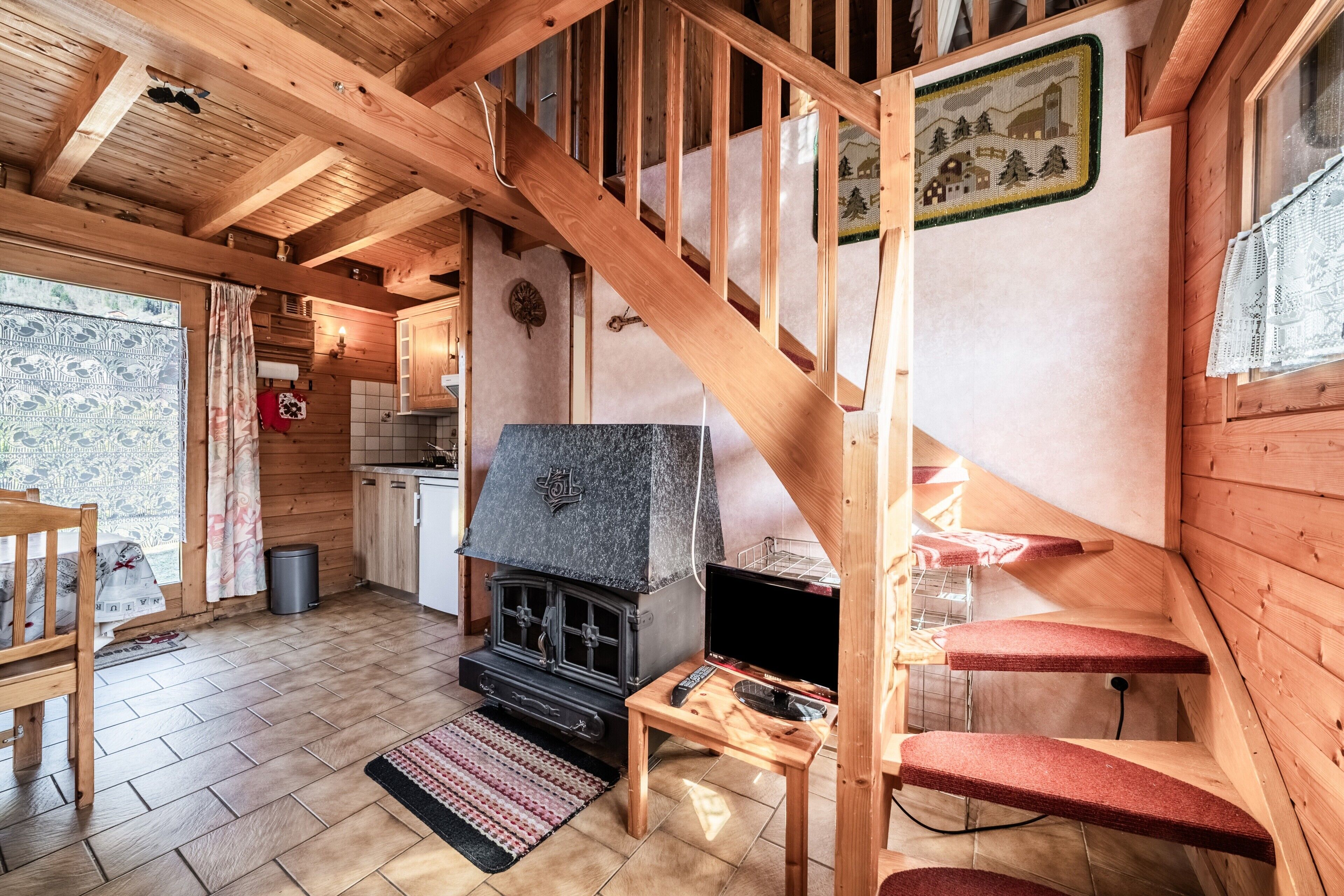 Un intérieur en bois avec une cheminée, un escalier et un coin cuisine.