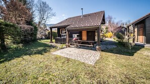 A rustic cabin with a tiled roof, a wooden deck, and a brick pathway leading to the entrance. - Chalet “6p Comfort – Le Grand Tétras”: Mountain View, Private Terrace & Wi-Fi (Verchaix)