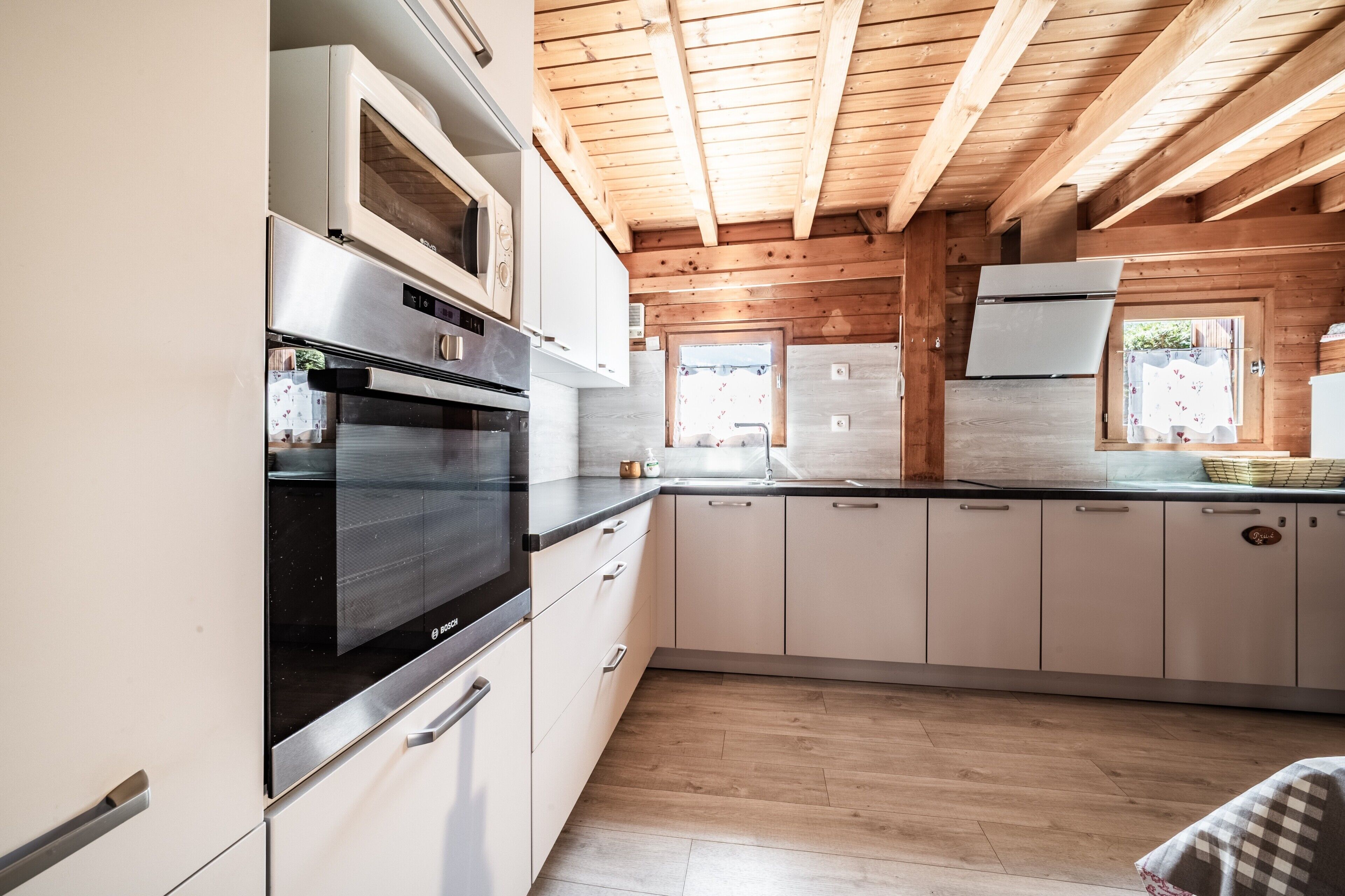 Una cocina moderna con electrodomésticos de acero inoxidable, vigas de techo de madera y vistas al exterior.