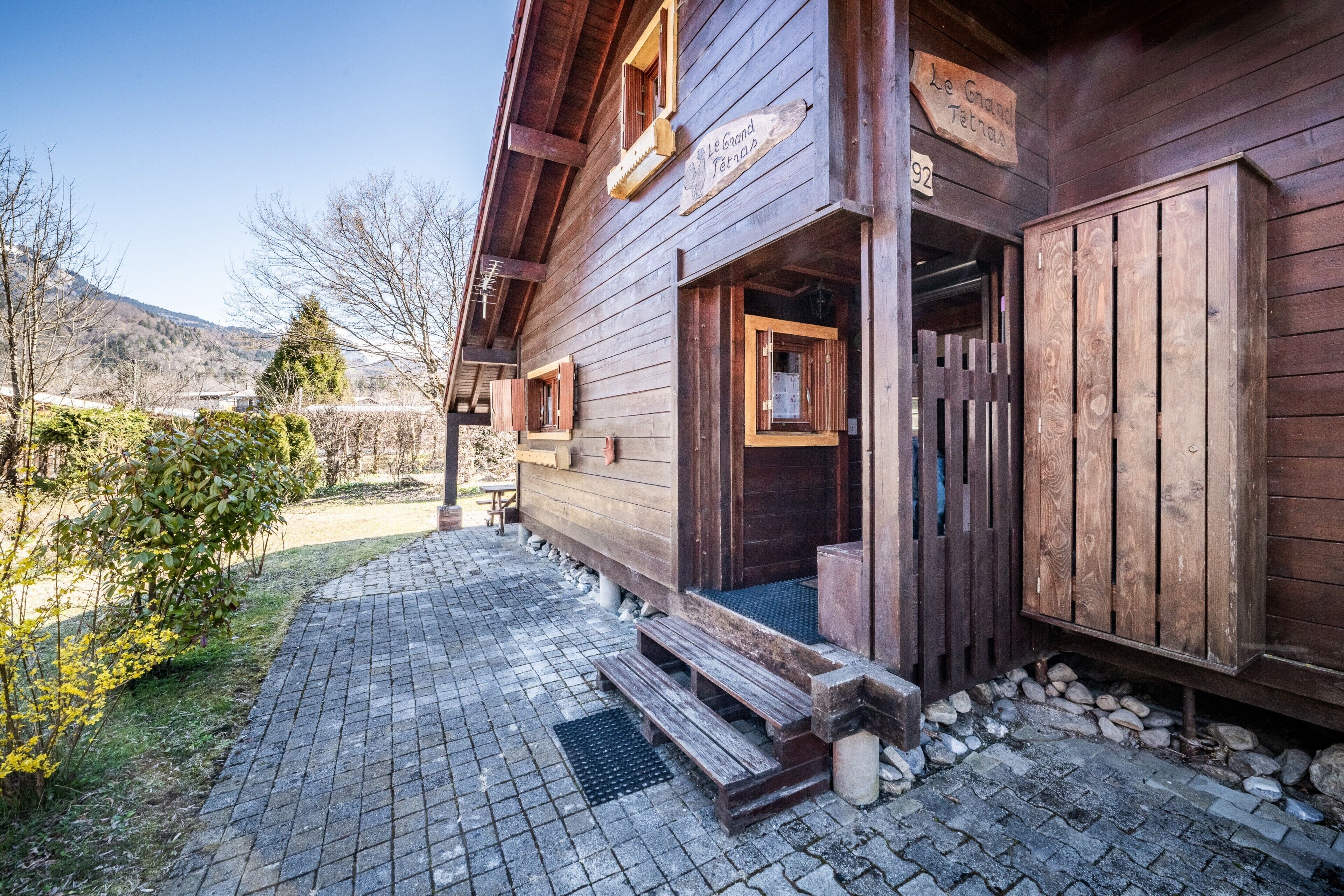 Un edificio in legno con un cartello che riporta 'Le Grand Tetra', una porta di legno e un'area pavimentata con gradini che conducono all'ingresso.