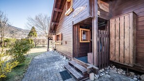 A wooden building with a sign reading 'Le Grand Tetra,' a wooden door, and a paved area with steps leading to the entrance. - Chalet “6p Comfort – Le Grand Tétras”: Mountain View, Private Terrace & Wi-Fi (Verchaix)