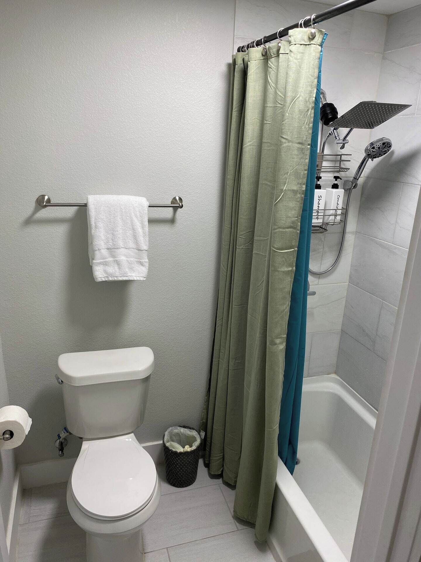 Et badeværelse med toilet, bruser og et håndklædetørrestativ.