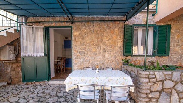 Un patio al aire libre con piso de piedra, una mesa con mantel y sillas.