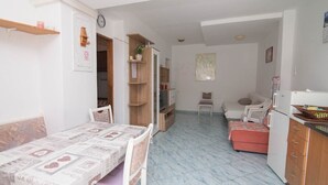 A compact room with a bed, a small desk, a chair, a kitchenette, and a door leading to another room. - Zdenka / Rovenska in Veli Lošinj (Veli Lošinj)