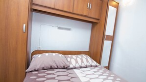 A bedroom with a bed, wooden wardrobe, and a wall-mounted light fixture. - Zdenka / Rovenska in Veli Lošinj (Veli Lošinj)