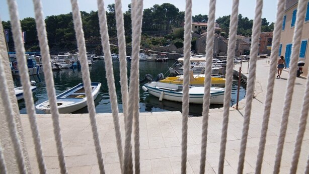 A marina with boats docked, a pedestrian walkway, and buildings with blue shutters in the background. - Zdenka / Rovenska in Veli Lošinj (Veli Lošinj)