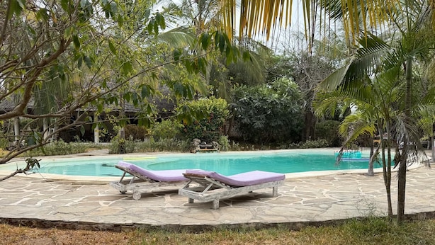 Ein Poolbereich mit zwei Liegestühlen und einer Terrasse mit Steinplatten.