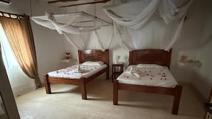 Ein Zimmer mit zwei Holzbetten, einem Deckenventilator und einem Moskitonetz.