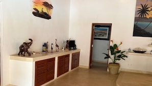 Ein Empfangsbereich mit Theke, Holzkästen, einer Zimmerpflanze und Bildern an der Wand.