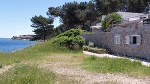 A stone building with a stone wall, a pathway, and a view of the sea. - Lacic / Lacic B4 in Mali Lošinj (Mali Lošinj)