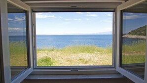 A window with a view of a grassy area and a body of water. - Lacic / Lacic B4 in Mali Lošinj (Mali Lošinj)