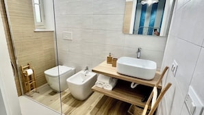 A modern bathroom with a bidet, a sink, and a mirror.