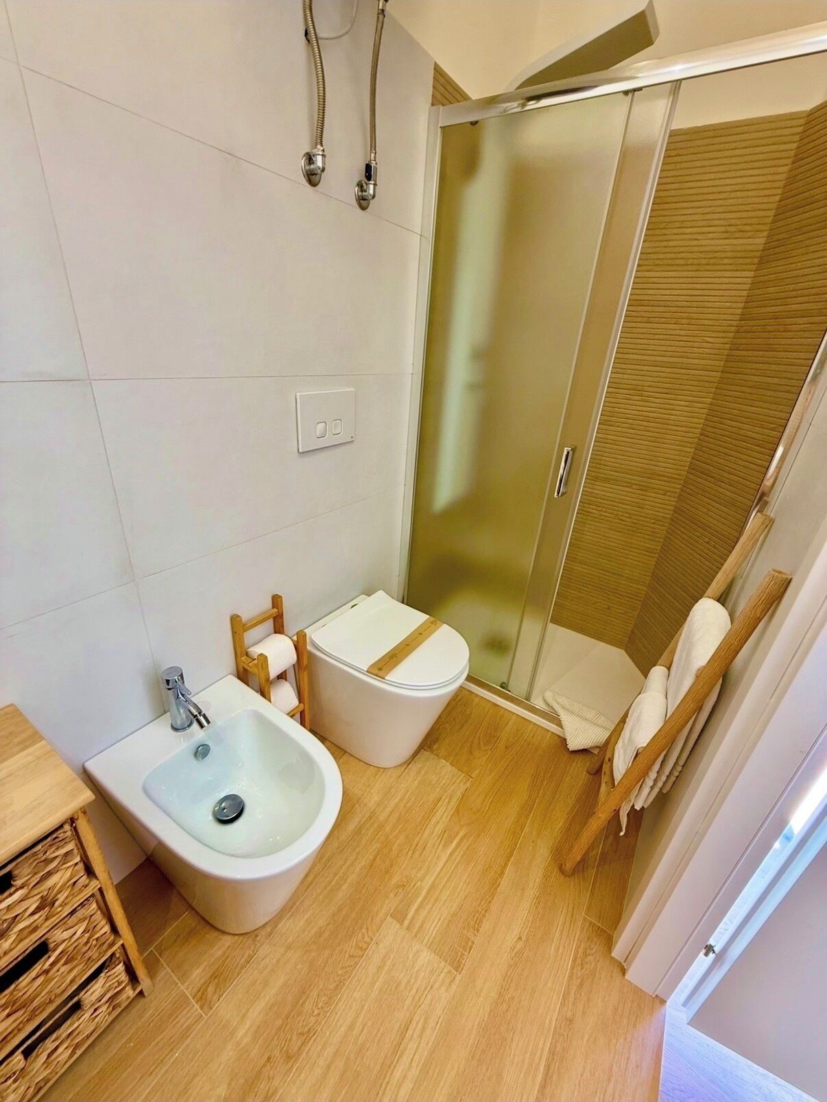 A modern bathroom with a glass shower enclosure, a bidet, and a toilet.